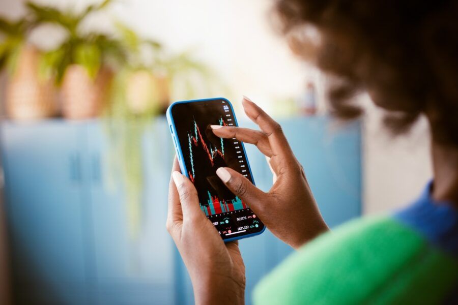 A woman using smart phone at home, watching stock charts.