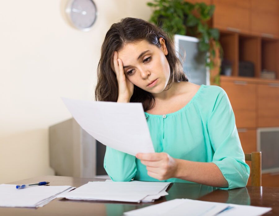 Woman stressed about late and missed payments, reading a note