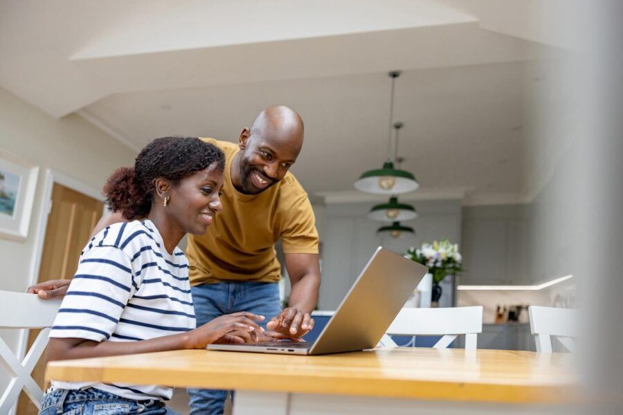 Smiling young couple filing taxes online at home