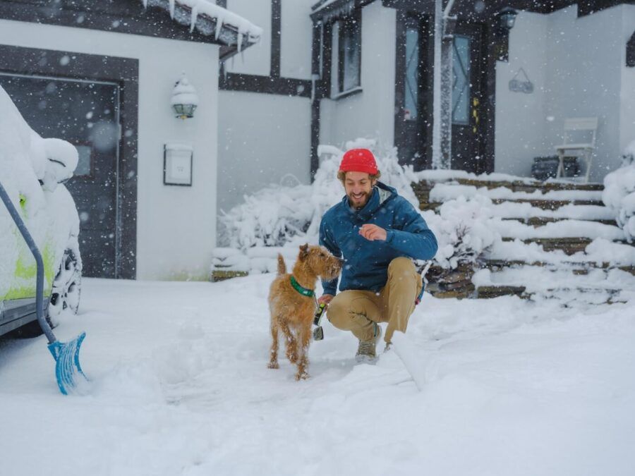 Cheerful man walking his dog in a snowy day