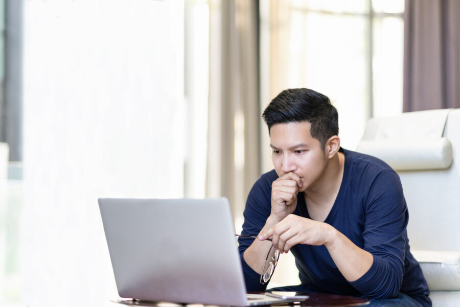 A man looking concernedly at his laptop while learning about the potential of defaulting on a personal loan.