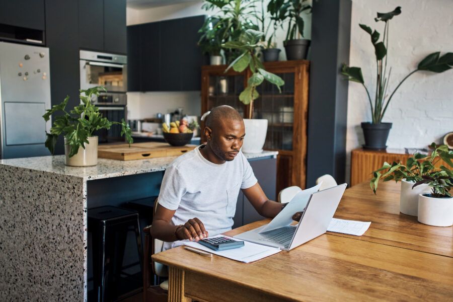 Man working on his taxes in his kitchen, researching taxes on dividend income.