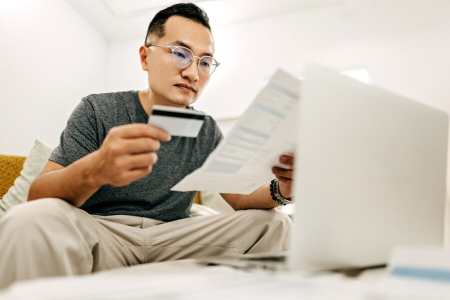 Man reviewing credit card bill holding credit card at home