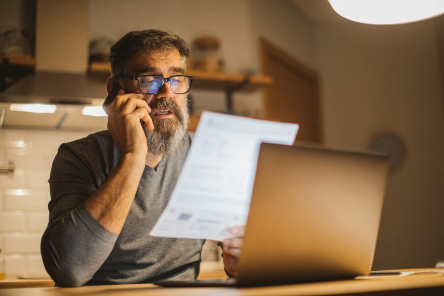 Mature men at home reviewing tax forms and talking on the phone