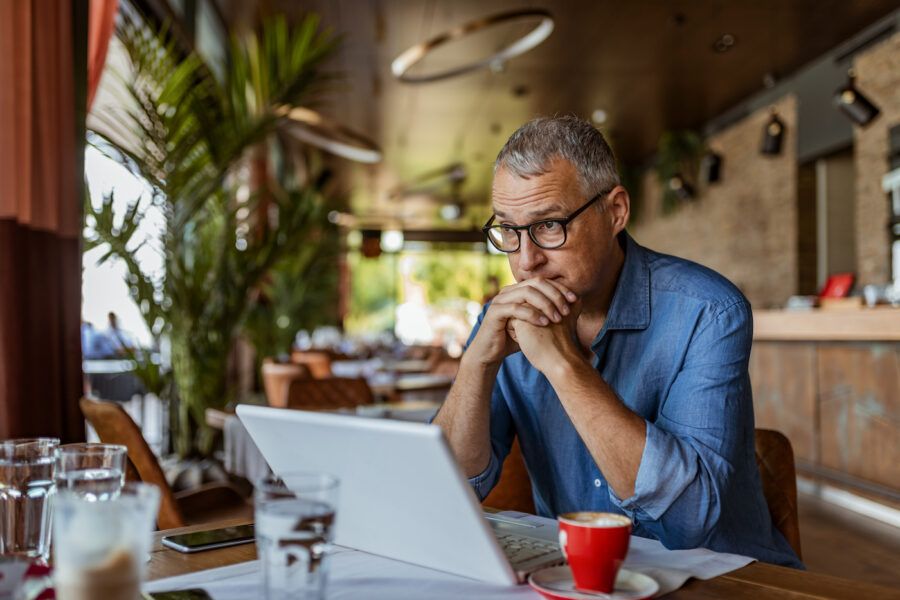 Man sitting in a coffee shop stressing about a potential recession