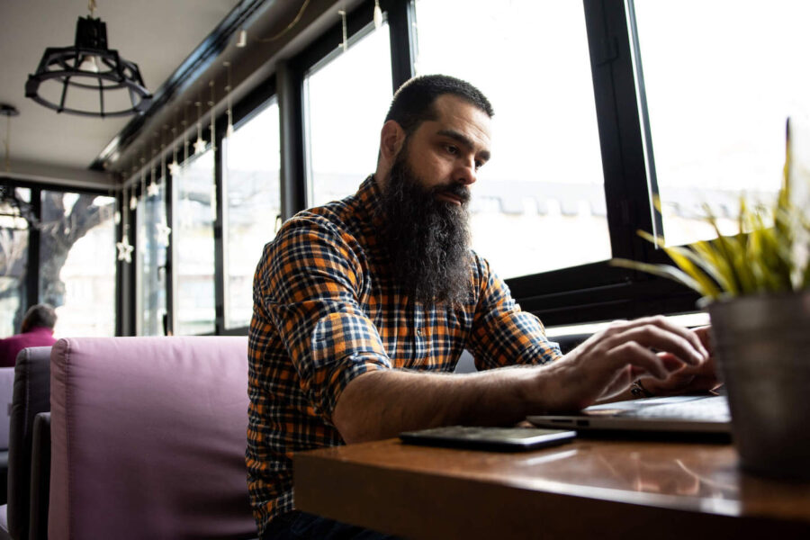 Man with checked shirt and long beard researching online how to switch banks.