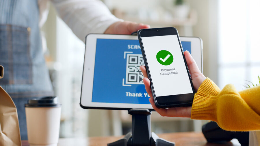 QR code payment, customer using peer-to-peer payment on their smartphone for paying at shop