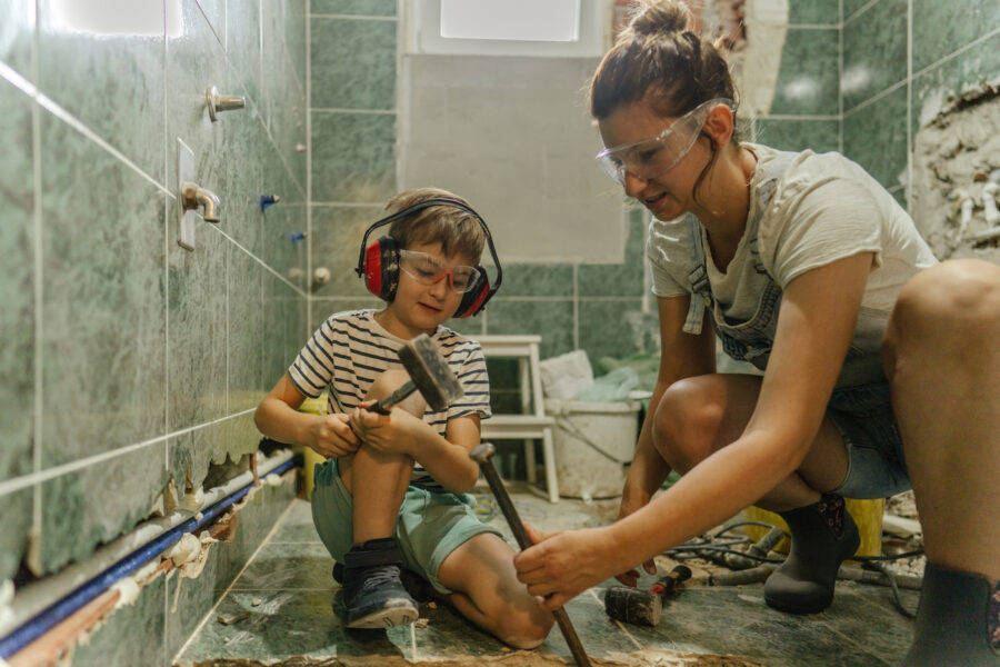 Photo of a mother and her young son, demolishing bathroom tile together
