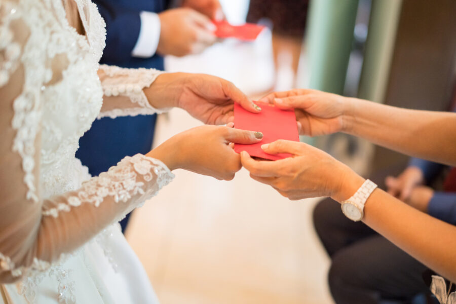 Guest giving red packet to newlywed couple