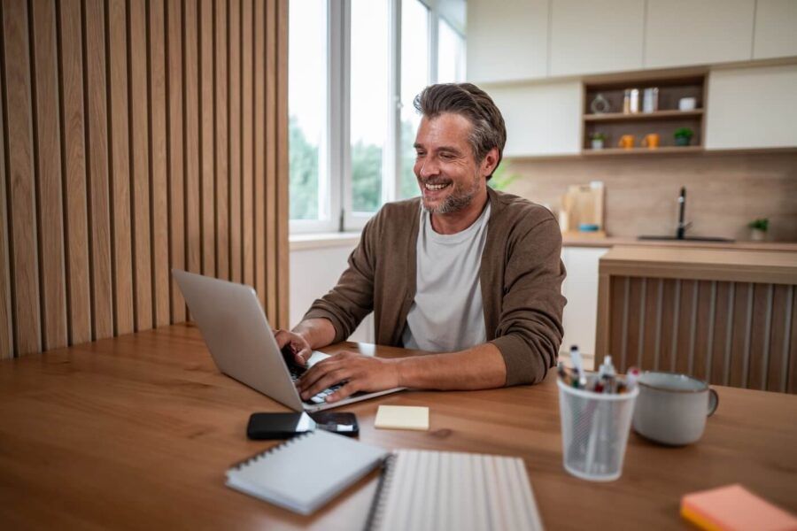 Smiling mature man using his laptop at home