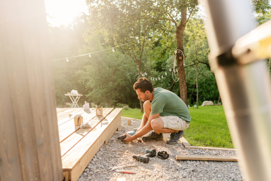 Photo of a man repairing deck of a house.