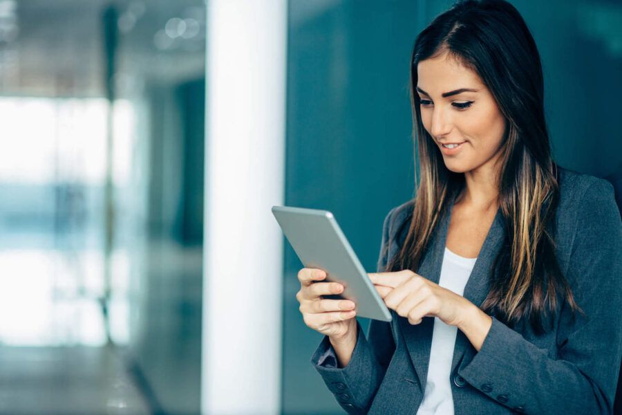 Portrait of young woman in business wear holding a digital tablet, with copy space.