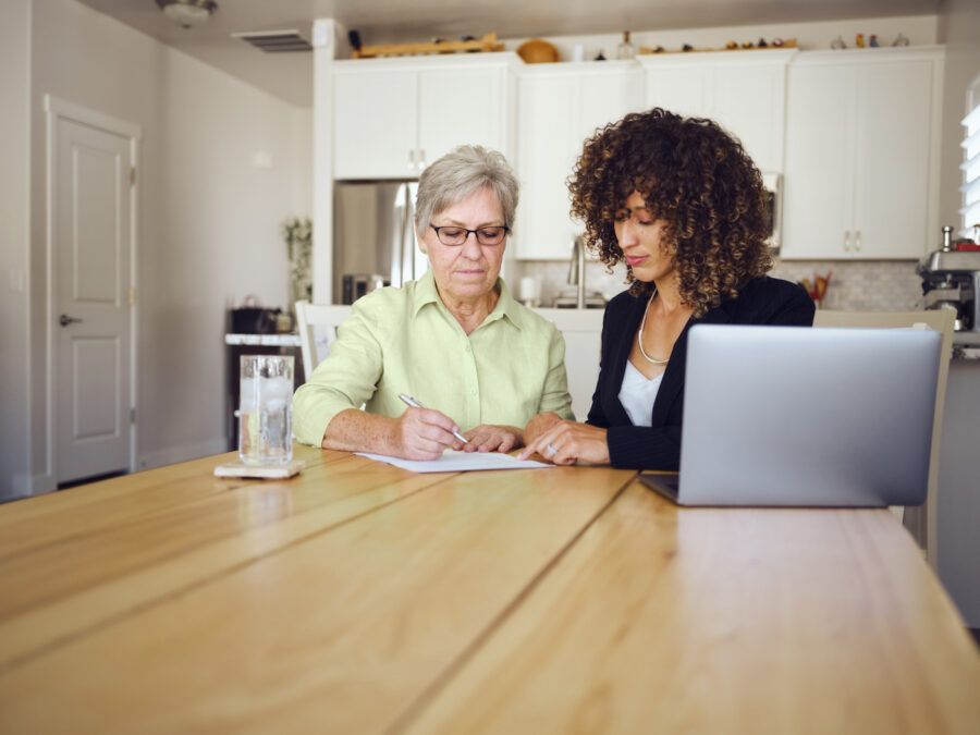 Two women cosigning a loan at a kitchen table.