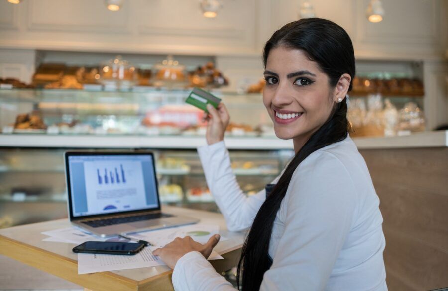 A business owner of a coffee shop doing the bookkeeping and holding a credit card.