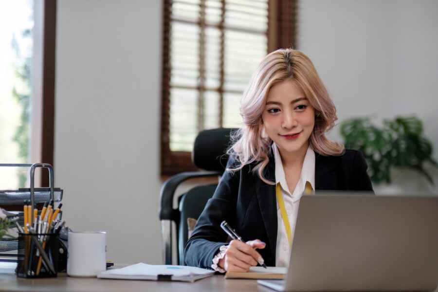 Business woman using laptop on wooden desk in office.