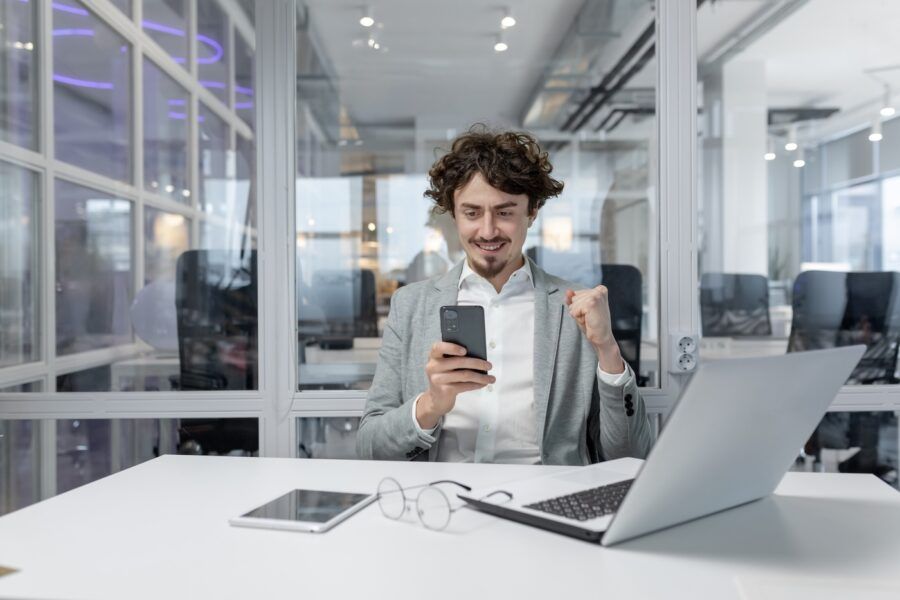 Young adult businessman using his phone in a modern office.