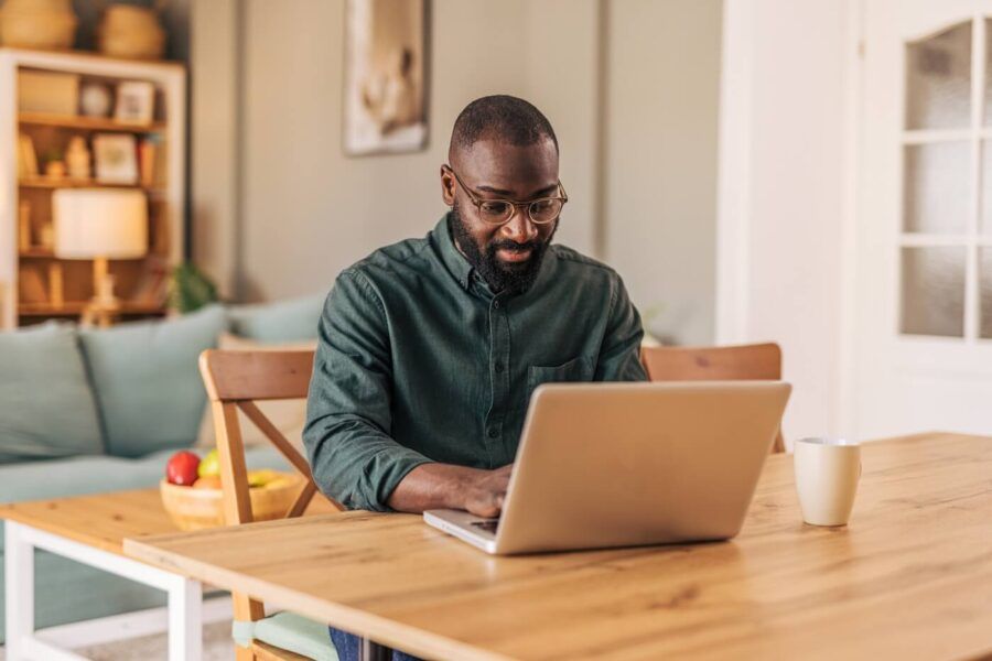 Man using his laptop at home in a sunny living room