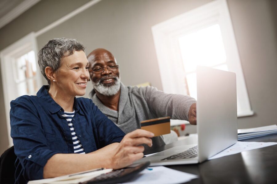 Shot of a senior couple using a credit and laptop while working on their finances at home.