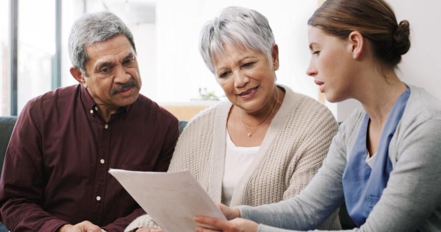 Shot of a senior couple reviewing Medicare plans with a doctor at home