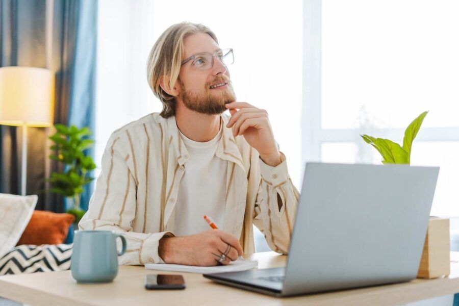 A man with a laptop is making financial decision in a sunny room