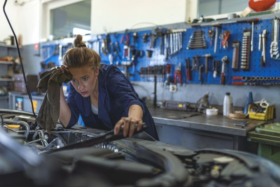 Female mechanic working under the hood of a car.