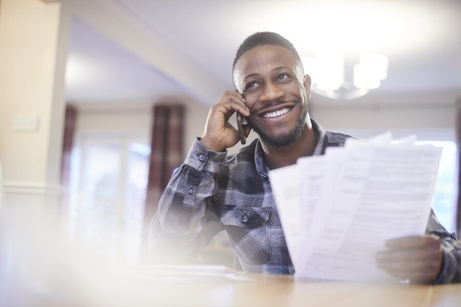 Young man on the phone holding paperwork.