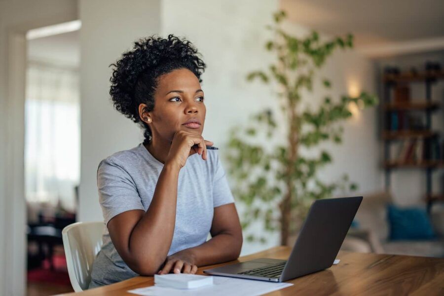 Pensive woman sitting at her desk with an open laptop
