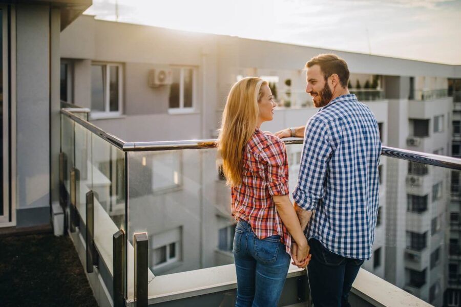 Young couple holding hands while standing on their condo terrace