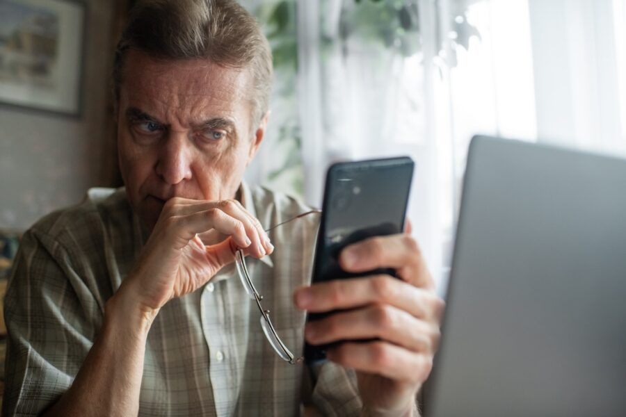 Senior man looking warily at his smartphone.