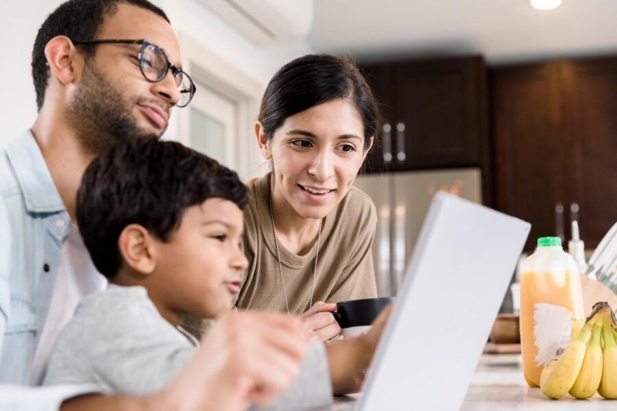 Small family watch something on laptop together.