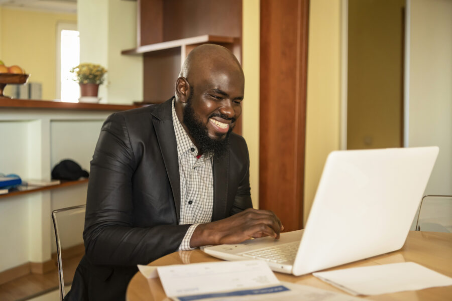 Man smiling looking at his laptop learning how to deal with high mortgage rates