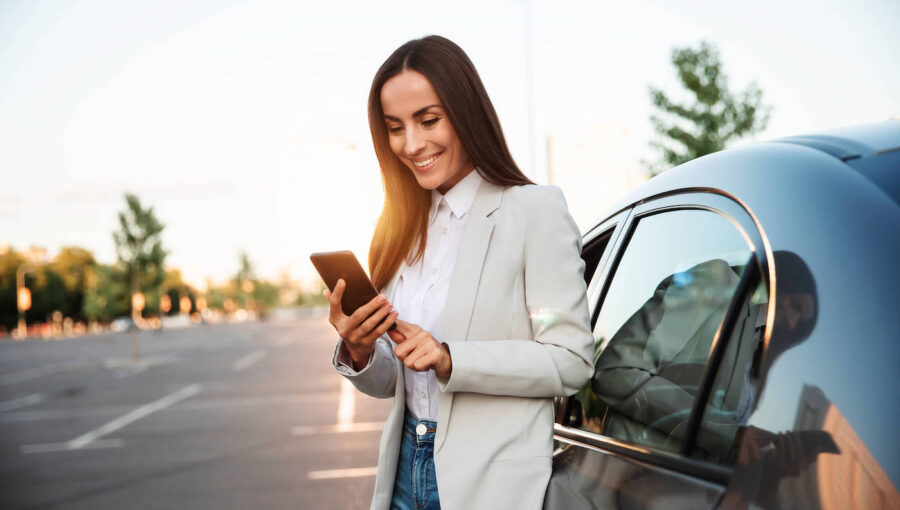 Smiling woman beside a car looking up how to make car last longer.