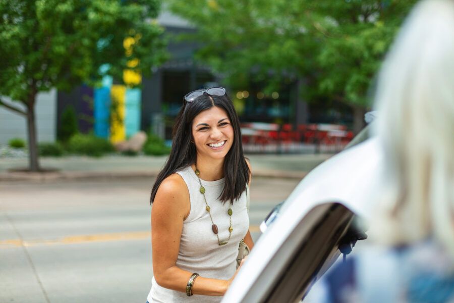 Woman standing in front of car talking to her friend