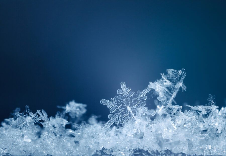 Macro of snowflakes in snowdrift over blue background at snowy night
