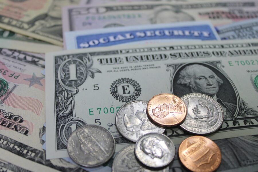 Closeup of US dollars, coins, and social security card in an economic collage.