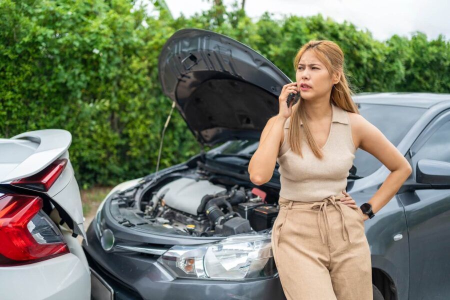 Concerned woman is making a phone call to her insurance company after a car accident