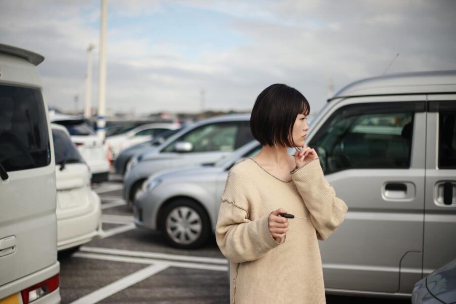 Concerned young woman using car keys to find her car in the parking lot