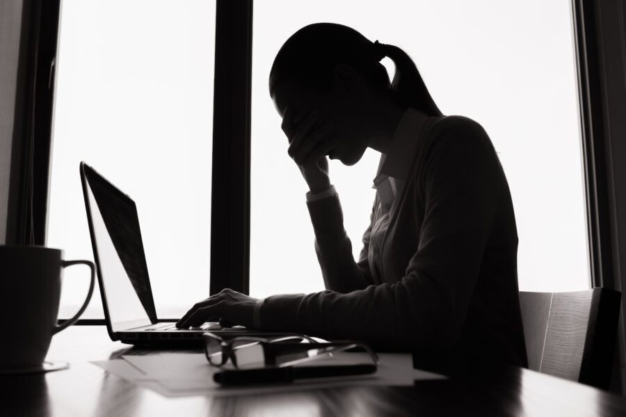 Stressed woman in front of a computer, dreading the resumption of student loan payments.