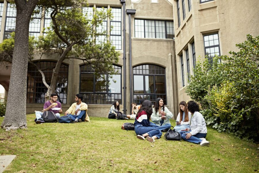 College students sitting on grass, talking.
