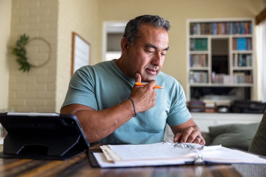 Mature man working on his taxes at home using a computer.