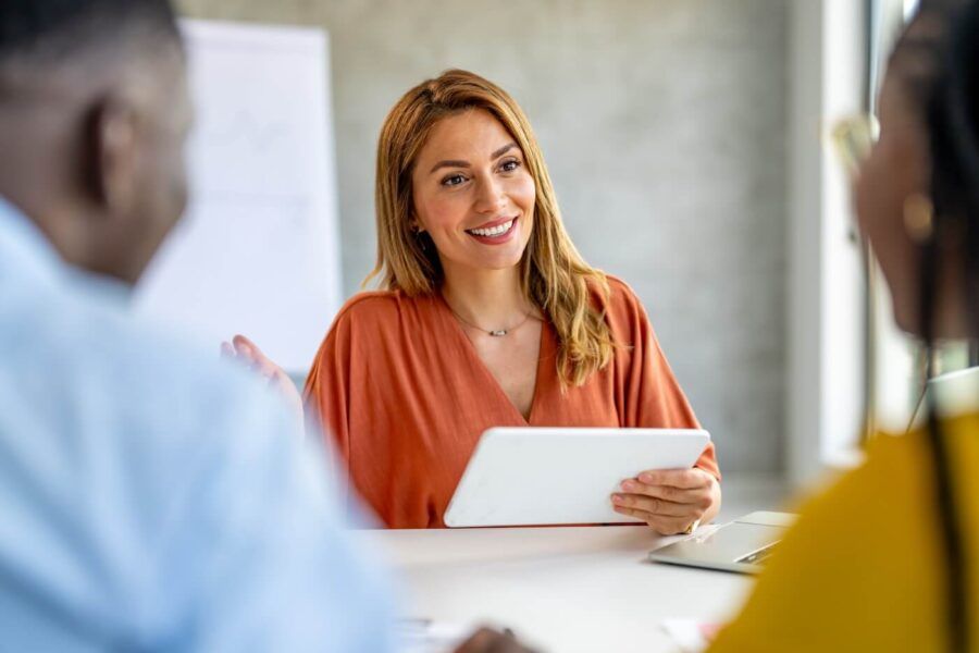 Female financial consultant sitting with a couple in her office, reviewing and discussing financial documents together