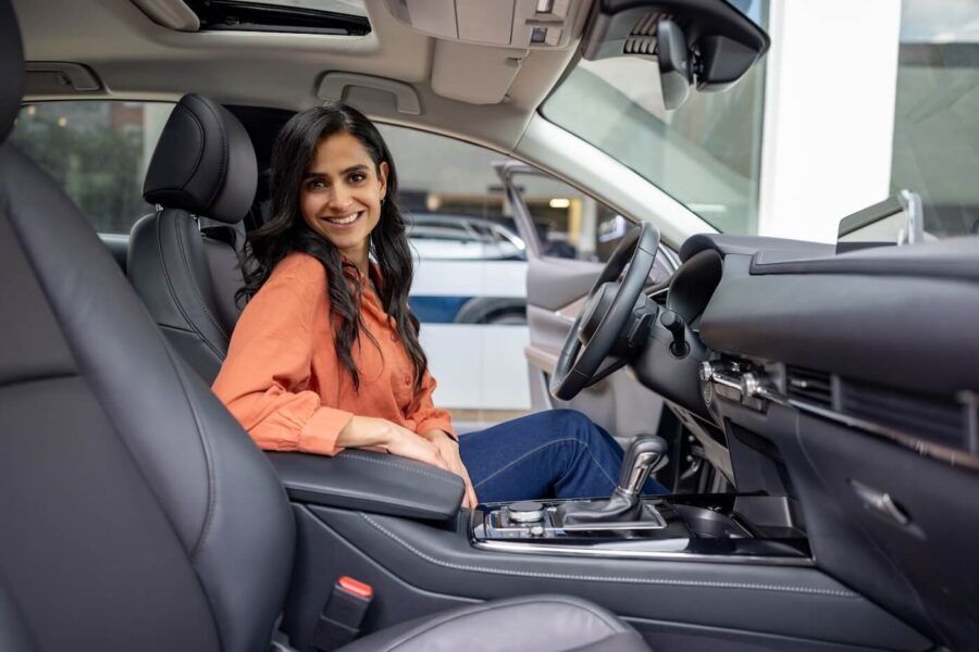 Smiling young woman sitting in her new car
