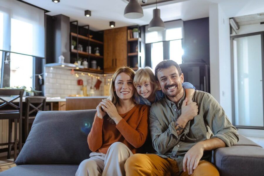 Happy family of three sitting on a couch in the living room