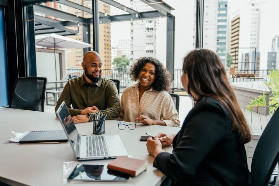 Happy couple talking to the real estate agent in her office