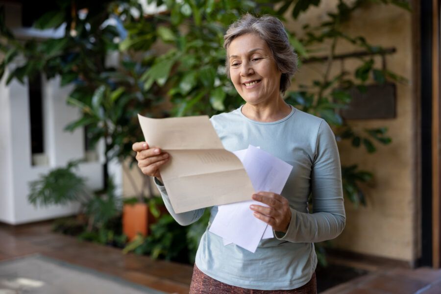 Happy senior woman at home reading a letter she got in the mail