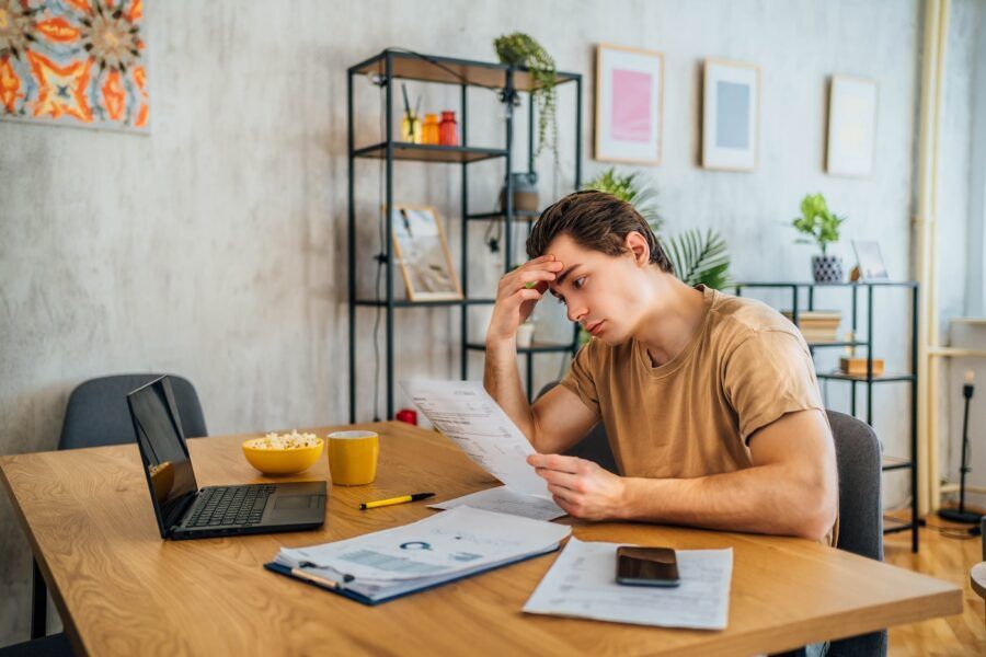 Young worried man managing his finances at home.