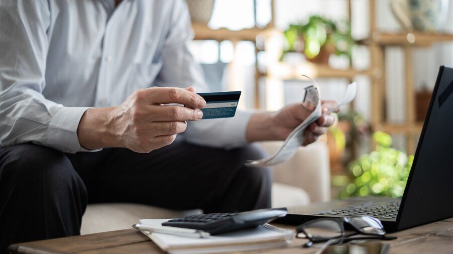 Close-up senior man pays bills with credit card