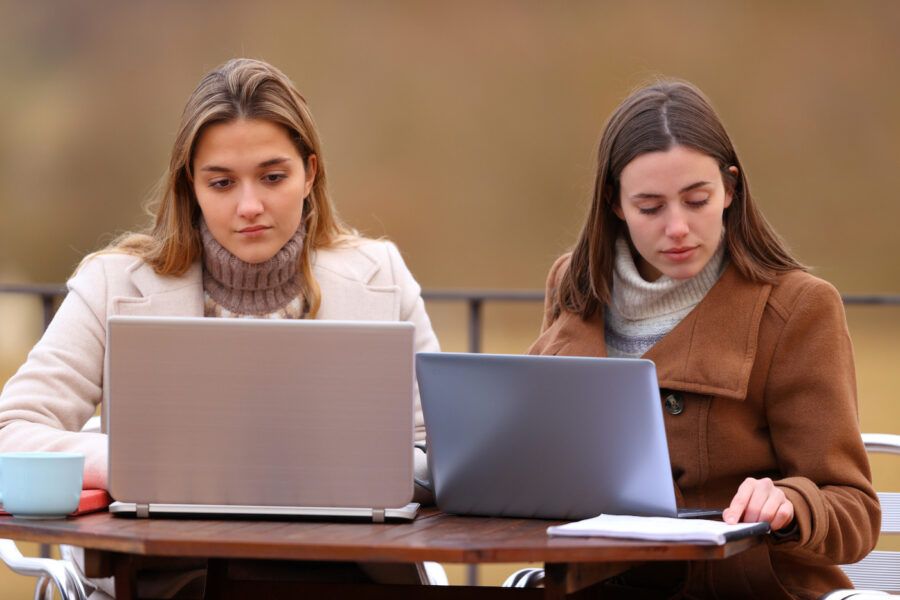 Two women using laptops in winter