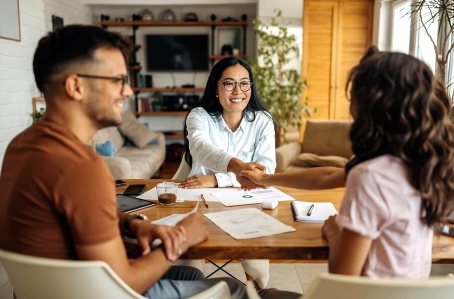 Female real estate agent shaking hands with the young couple