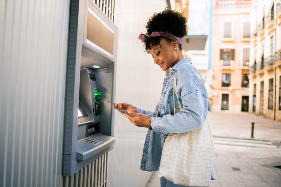 Smiling young woman using ATM